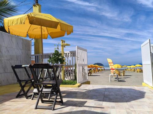 een tafel en stoelen onder een gele parasol op het strand bij Recanto Guaraú 4 in Peruíbe