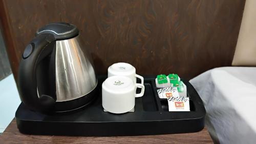 加姆布Airport Hotel The Paramont Palace Inn New Delhi的咖啡壶和桌子上的两个杯子