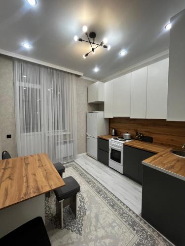 Квартира في Taldykolʼ: مطبخ مع طاولة خشبية ودواليب بيضاء