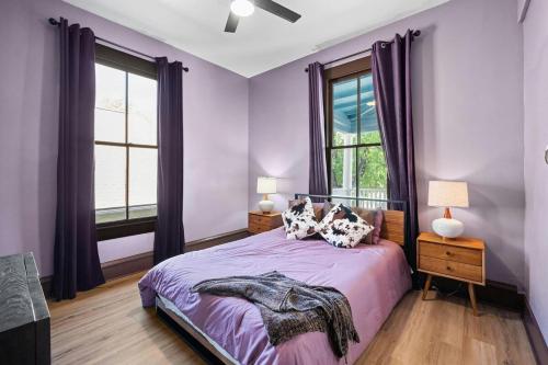 a bedroom with purple walls and a bed with two windows at Historic French Royal Estate at Capitol, Downtown! in Austin