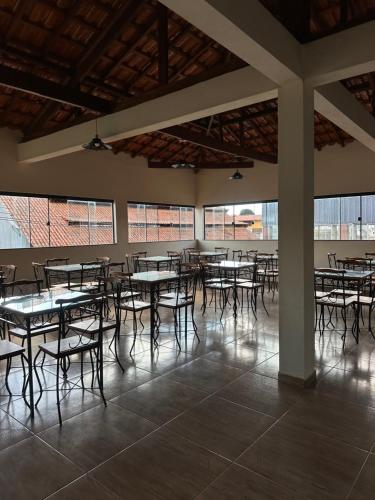 Pousada Recanto das Bromélias في ساو ثومي داس ليتراس: غرفة فارغة فيها طاولات وكراسي ونوافذ
