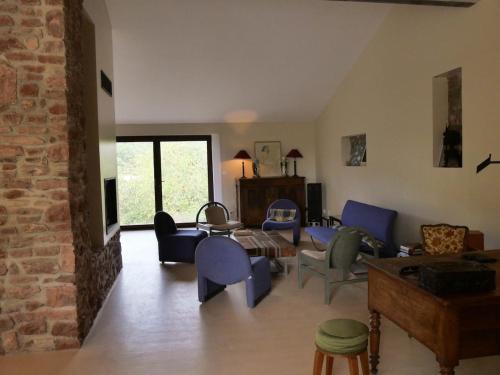 a living room with blue chairs and a brick wall at Domaine la Pause in Aveyron in Vabres-lʼAbbaye