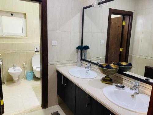 ein Badezimmer mit zwei Waschbecken und einer Toilette und einem Spiegel in der Unterkunft Furnished Villa in Andalusian Compound for Rent in Madaba