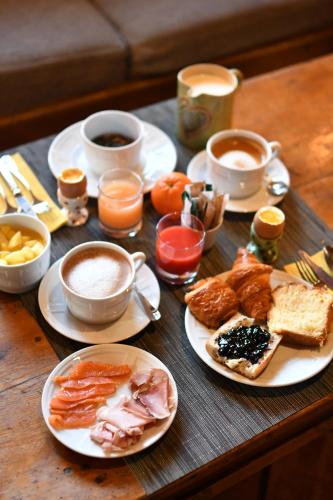 a wooden table with plates of food and cups of coffee at Au Coin Du Feu in Megève
