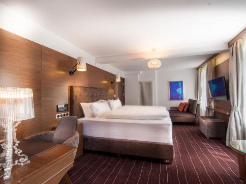 ein Hotelzimmer mit einem großen Bett und einem Sofa in der Unterkunft arthausHOTEL in Davos