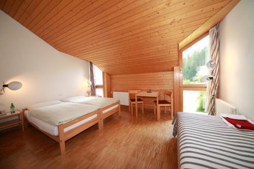 1 dormitorio con 2 camas y techo de madera en Hotel Albula & Julier, en Tiefencastel