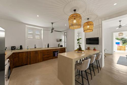 威廉斯塔德Kas Leon - Villa Heritage Retreat的厨房里有两盏枝形吊灯和一个带椅子的吧台。