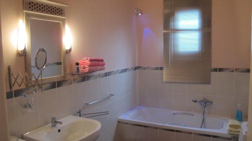 une salle de bain avec une baignoire, un lavabo et un miroir dans l'établissement Aemilianus Nest Cottage, à Loutrá Kounoupélli