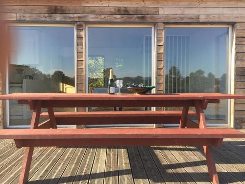 un banc de pique-nique rouge installé sur une terrasse en bois dans l'établissement Maison bois proche de l' A6, à Brianny