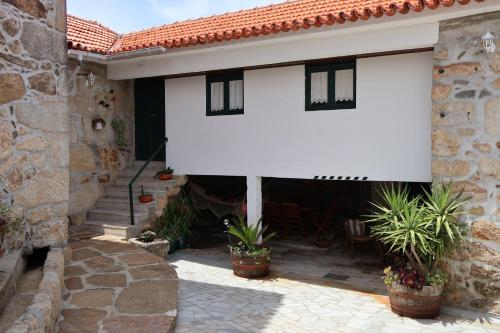 a white house with potted plants on a patio at Quinta da Lage Agroturismo e Enoturismo in Celorico de Basto