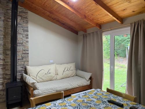 Una sala de estar con una cama y una ventana. en CABAÑAS AILIN-CO, en El Bolsón