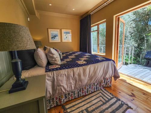 una camera da letto con un letto con una lampada e una finestra di Villa Candle Berry - Tranquil Lagoon Retreat a Brenton-on-Sea