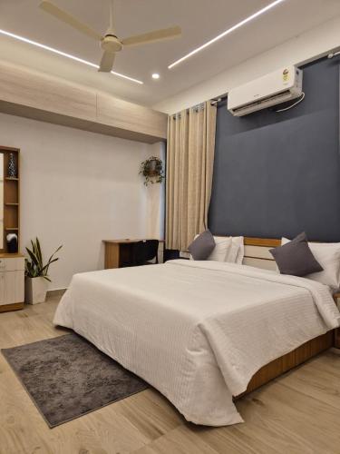 Un dormitorio con una gran cama blanca y una pared azul. en Willow The Villas, en Mananthavady
