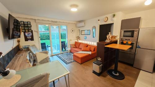 een woonkamer met een oranje bank en een keuken bij Anton's Home in LʼHay-les-Roses