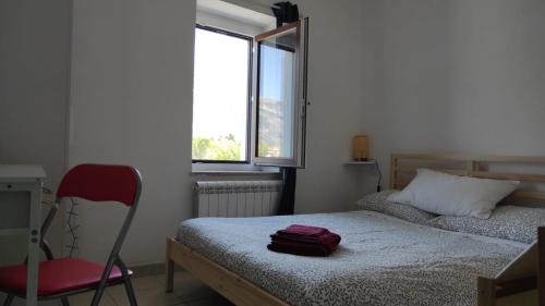 a bedroom with a bed and a chair and a window at L'angolino di Ale in Sulmona