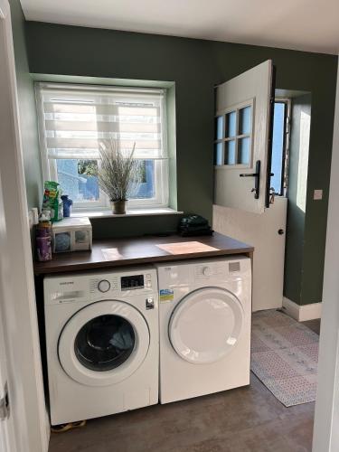 a laundry room with a washing machine and a window at The riverside place in Newry