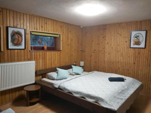 - une chambre avec un grand lit et des murs en bois dans l'établissement Squirrel cottage, à Dolná Lehota