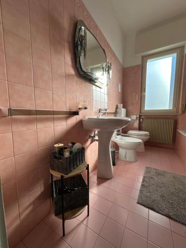 une salle de bains rose avec lavabo et toilettes. dans l'établissement Tre Aceri Comfort House, à Udine