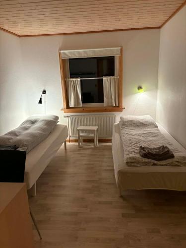 une chambre avec deux lits et une fenêtre dans l'établissement Midbrekkan Guesthouse, à Tvøroyri