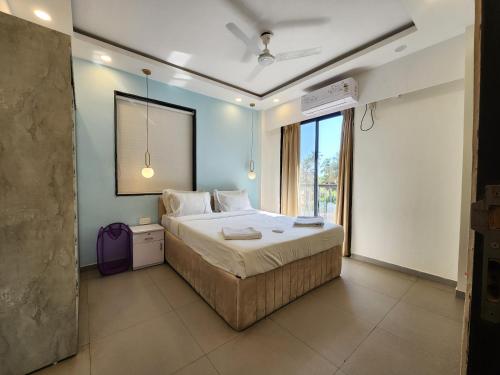 Un dormitorio con una cama grande y una ventana grande. en Calm 1BHK Modern Apartment in Candolim with Pool, Balcony & Modern Decor, en Candolim