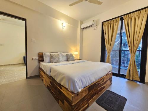 Serene 1BHK Getaway Apartment in Candolim Goa with Pool, Balcony & Kitchen في كاندوليم: غرفة نوم بسرير كبير ونافذة كبيرة