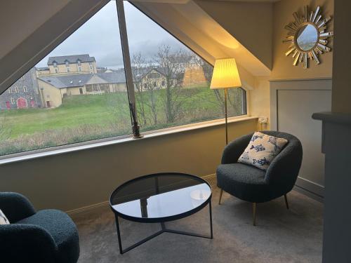 sala de estar con 2 sillas, mesa y ventana grande en The Boutique Bungalow, en Bundoran