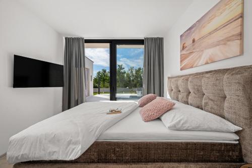 ein Schlafzimmer mit einem großen Bett mit einem großen Fenster in der Unterkunft Santalezi Sunset Villa 2 in Santalezi