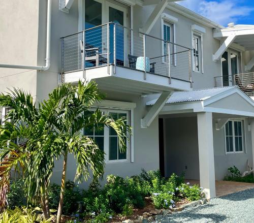 a white house with a balcony and palm trees at Pond Bay Paradise Villa Ocean Views Beach and Kayaks in Monte