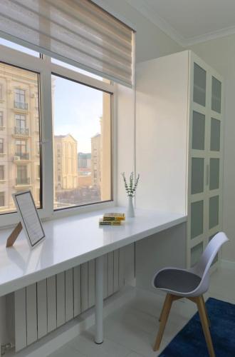 una scrivania bianca con sedia e finestra di Апартаменты рядом с Пирамидой a Astana