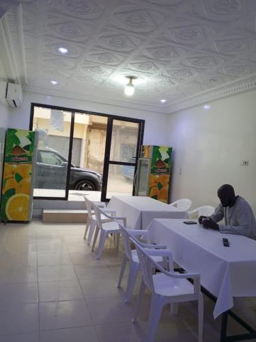 Ein Mann, der im Esszimmer an Tischen sitzt. in der Unterkunft La PERLE NOIRE Dakar, Guédiawaye, Cité Cour Suprême in Dakan