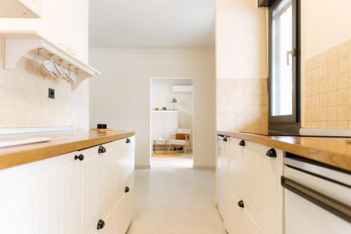 eine Küche mit weißen Schränken und einem Fenster in der Unterkunft Spacious 1BR Designer Apartment in Sloboština in Zagreb