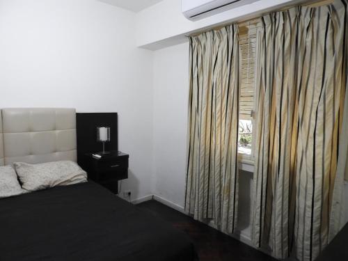 een slaapkamer met een bed en een raam met gordijnen bij Departamento Centro BA in Buenos Aires