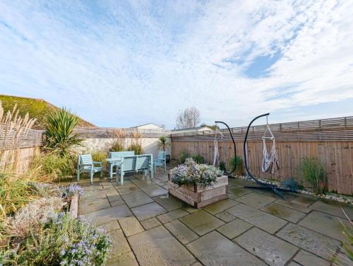 a patio with a table and chairs and a fence at Sanderling House, walk to beach in Earnley