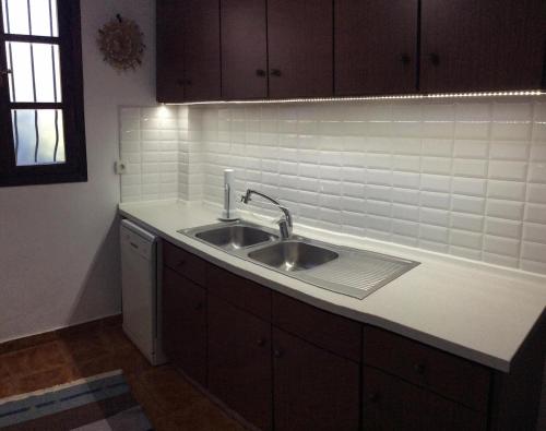a kitchen with a sink and a white tile wall at Kolymbia home in Kolymbia