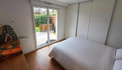Anton's Home في LʼHay-les-Roses: غرفة نوم بها سرير أبيض وباب زجاجي منزلق