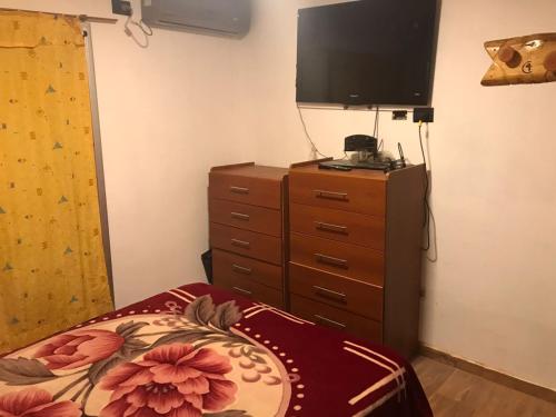 a bedroom with a bed and a dresser with a television at Las Catitas in Villa del Lago