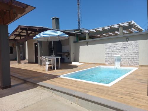 einen Pool mit einem Tisch und einem Sonnenschirm in der Unterkunft Casa Com Piscina Pertinho Do Mar Em Capão Da Canoa in Capão da Canoa