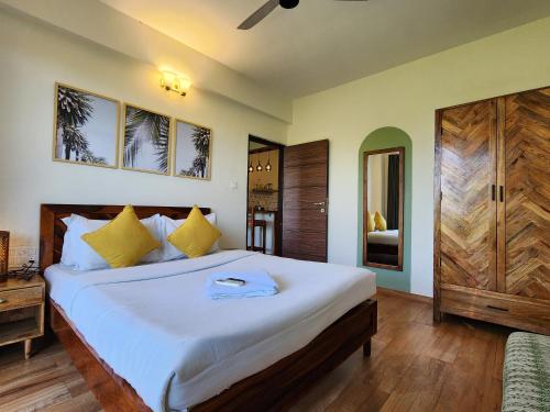 Warm 2BHK with Scenic Mangrove View in Candolim Goa في كاندوليم: غرفة نوم بسرير ابيض كبير مع مخدات صفراء
