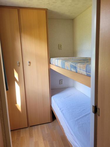 a small room with a bunk bed and a closet at Stacaravan 6 persoons - Camping Le Soustran in Neuvic