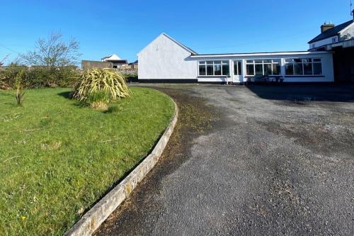 米尔敦马尔贝Station House Accommodation的前面有车道的大型白色房屋