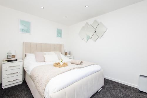 a white bedroom with a white bed and a white dresser at Modern Cozy Flat 6 mins to City Parking & WiFi in Killingbeck