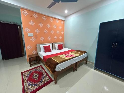a bedroom with a bed with a red wall at Kedar Guest House Ayodhya in Ayodhya