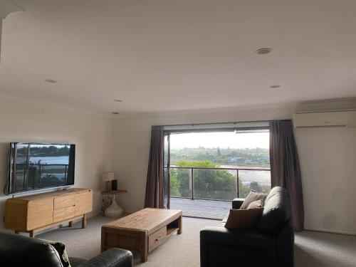 un salon avec un canapé et une grande fenêtre dans l'établissement Coastal Comfort - Views for the Whole Crew, à Tauranga