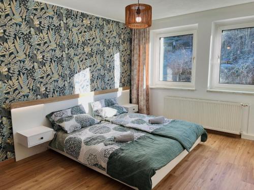 a bedroom with a bed and a wall covered in wallpaper at LilienNest - Stilvolles Apartment mit Panoramablick in Königstein an der Elbe