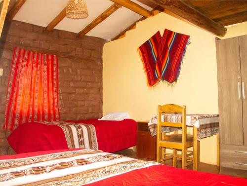 a bedroom with two beds and a table and a chair at Casa rústica Pumayalli in Urubamba