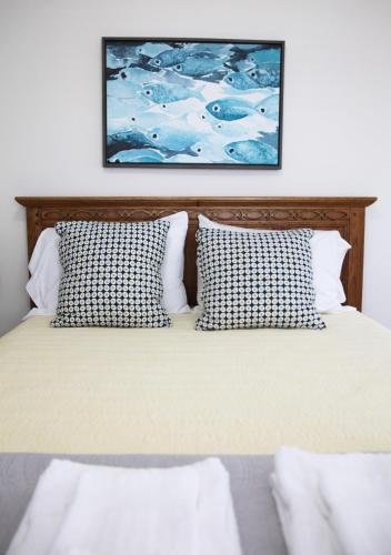 a bed with two pillows and a painting on the wall at 508 A The Shore Break Cottage in Virginia Beach