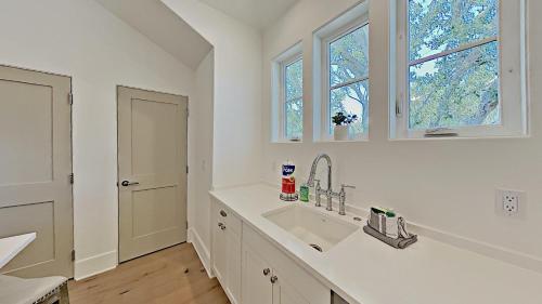 a white kitchen with a sink and two windows at Crystal Blue Persuasion in Santa Rosa Beach