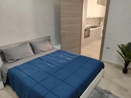 a large blue bed in a room with a kitchen at Al civico 14 in Foggia