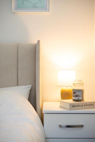 a bedroom with a bed and a nightstand with a lamp at Modern Cozy Flat 6 mins to City Parking & WiFi in Killingbeck