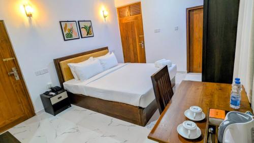 a bedroom with a bed and a wooden table with a table at Grand Toscana in Udawalawe